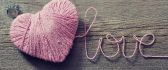 A pink heart made of wool on the wood