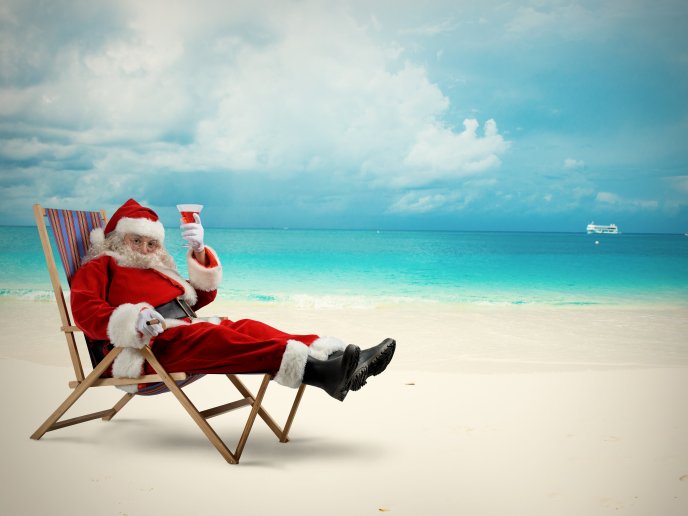 Happy Santa Claus drinking a cocktail on the beach