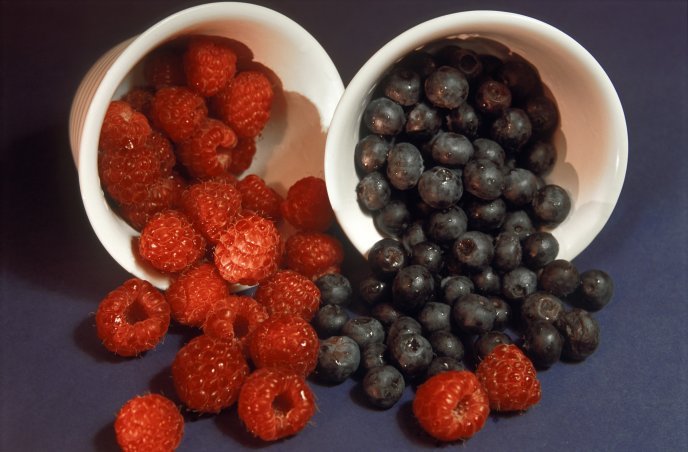 Delicious raspberries and blueberries in white cups