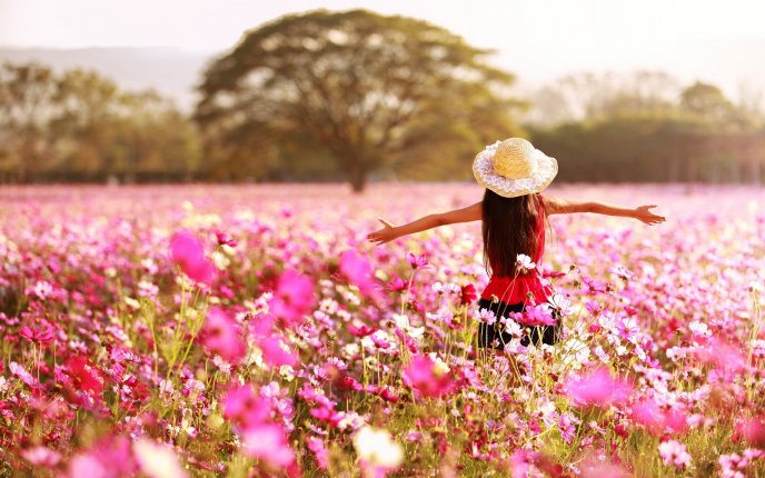 Happy girl in a field full with pink flowers - Spring season