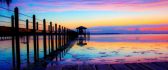 Rainbow colors of sunset over the ocean water and pontoon